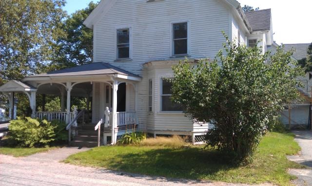 A photo of the PTLA Machias Office, a big old white house with a large porch and PTLA sign out front