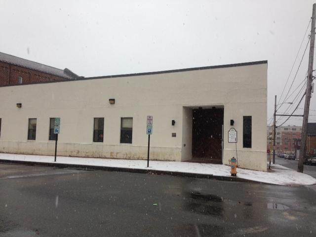A photo of the PTLA Portland office entrance, a ground-level beige building with a recessed entryway on a quiet, snowy Portland street.