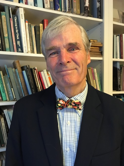 An older white man with short white hair smiles at the camera. He is wearing a suit jacket and bow tie.